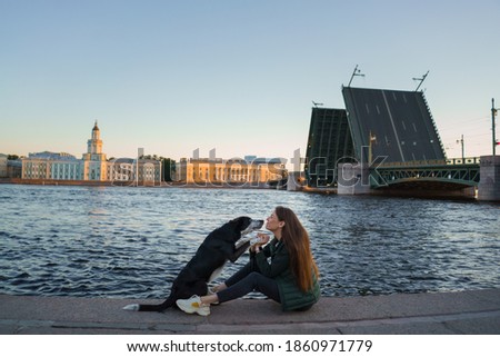 a girl and a dog on the background of drawbridges in St. Petersburg. Traveling with pet in the city