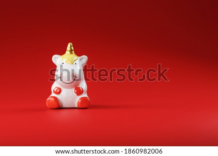 Unicorn figurine on a red background with free space.