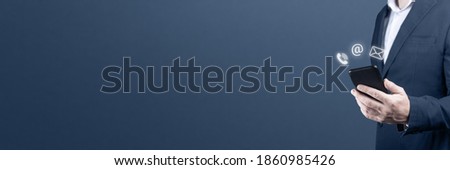 CONTACT US. businessman holding cell phone with with mail, phone, email icon. cutomer support concept. copy space. blue background Royalty-Free Stock Photo #1860985426