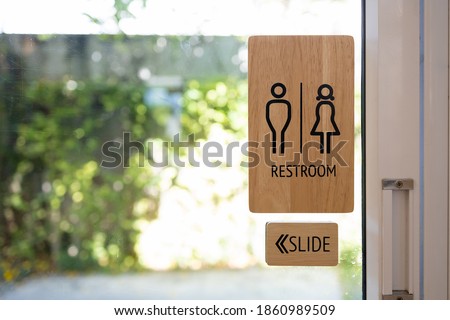 Toilets icon, Public restroom signs ,Wooden toilet sign and direction on glass door blurred background.