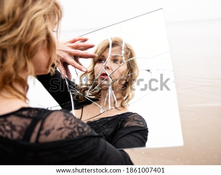 Woman looking at herself in broken mirror Royalty-Free Stock Photo #1861007401