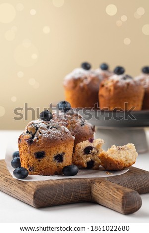 Blueberry muffins decorated with fresh blueberries and powdered sugar, without muffins cup, on white table, Selective focus. Copy space. Vertical image.