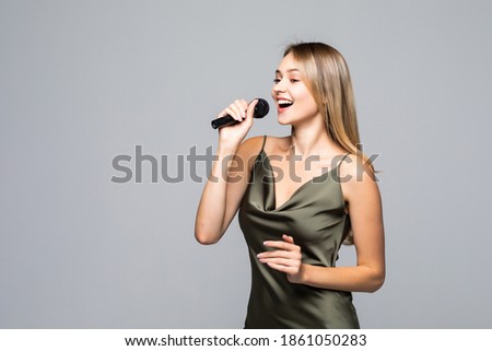 Beautiful girl with microphone on grey background