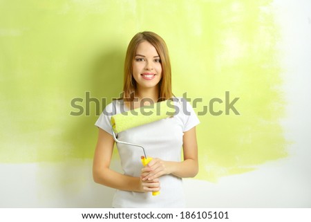Beautiful girl painting a wall. light background
