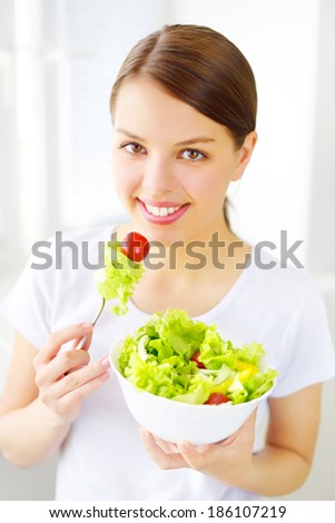 Teenager girl eating salad on light background