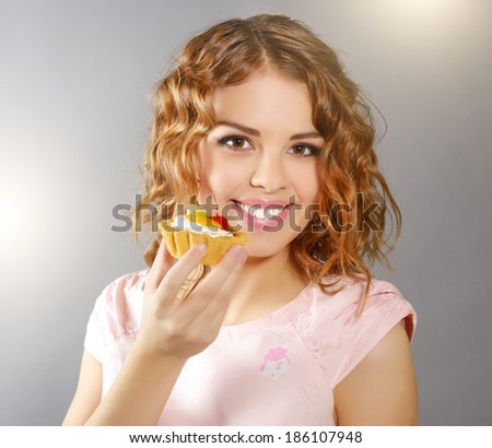 Smiling girl with cupcake on light background