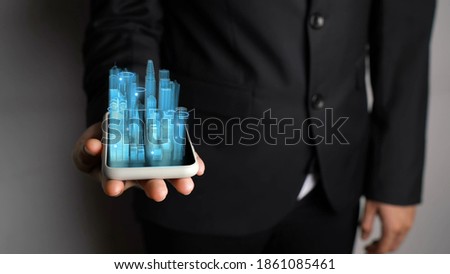 Businessman holds 3D city model showing augmented reality technology . Futuristic urban hologram screen in concept of virtual internet of things and global network connection .