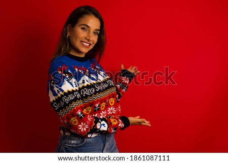 Young beautiful Hispanic woman wearing winter sweater against red wall Inviting to enter smiling natural with open hands. Welcome sign.