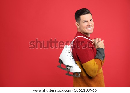 Happy man with ice skates on red background. Space for text