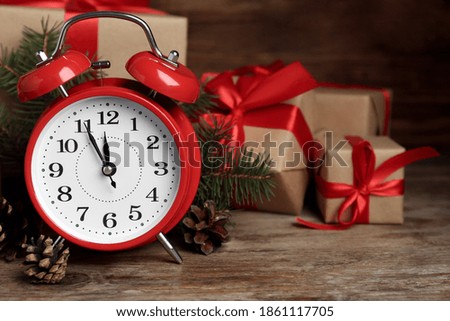 Christmas gifts, alarm clock and pine cones on wooden table, space for text. Boxing day