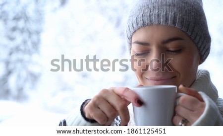 Portrait of the beautiful girl drinking hot tea in snowy winter