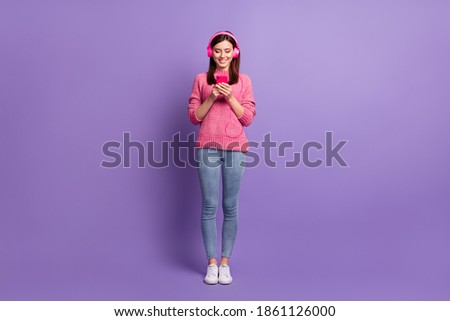 Full length body size photo of female blogger earphones with smartphone typing message isolated on vibrant purple color background