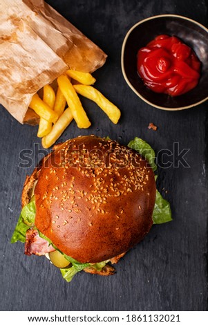 Fresh tasty burger with crunchy french fries on dark background