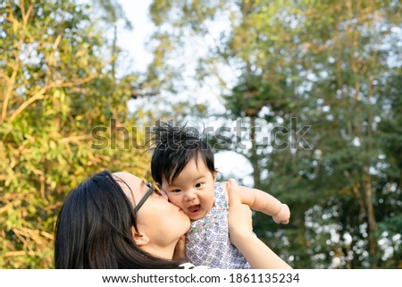 An Asian mother is holding her daughter and kissing on her cheek. A little girl is so happy.
Mother and daughter relationship.
