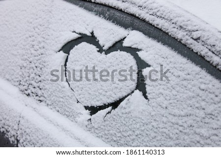 Finger picture symbol HEARTH on snowy side car glass in winter day february 14, close up view winter concept love symbol