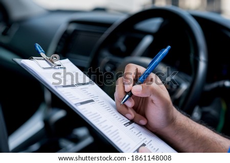 A car maintenance worker is checking a list of the car interior for a workshop customer. Royalty-Free Stock Photo #1861148008