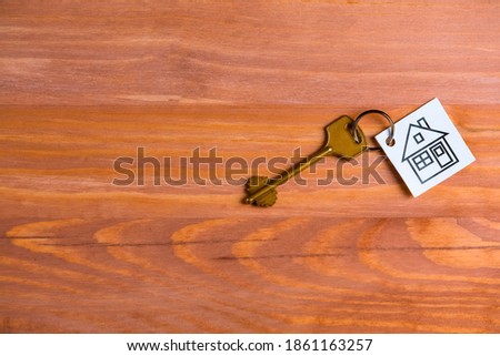 Home or House Symbol Along With Long Key Against Vintage Wooden Background. Horizontal Image