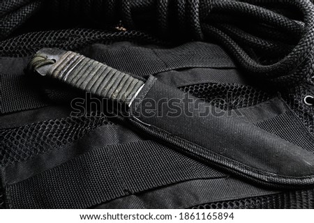 The knife lying in its scabbard in a braid of paracord lies on the assault unloading along with the rope Royalty-Free Stock Photo #1861165894