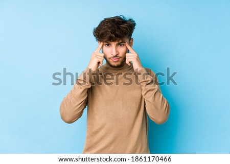 Young arabian man isolated focused on a task, keeping forefingers pointing head.