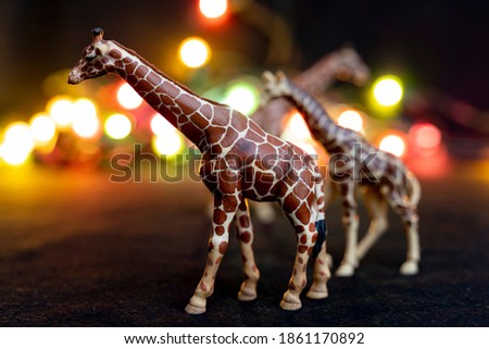 plastic figurines of giraffes in a savannah-like environment at night. children's toy. animal protection concept

