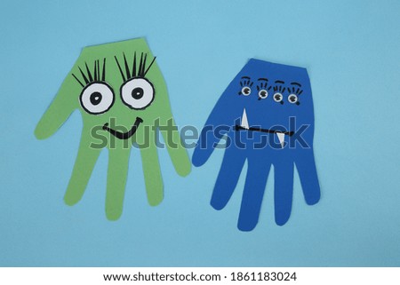 Funny hand shaped monsters on light blue background, flat lay. Halloween decoration