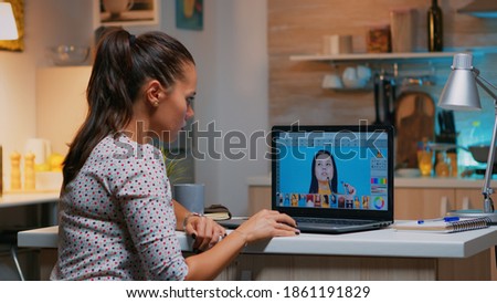 Freelancer retoucher woman working on laptop computer with photo editing software. Professional graphic editor retouching photos of a client during night time in home office on performance pc.