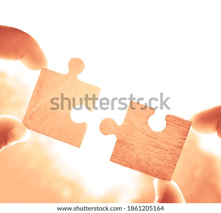 2 two hands of businessman to connect couple puzzle piece with sky background.Jigsaw alone wooden puzzle against sun rays.one part of whole.symbol of association and connection.business strategy