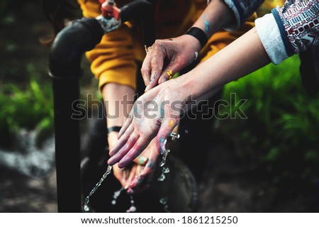 Shallow depth of field (selective focus) image with young women washing their hands from painting colors.