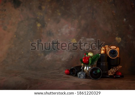 christmas and new year background for photographer. christmas set gold camera and lenses and christmas tree toys on dark background with soft selective focus. horizontal orientation