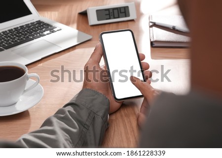 Man using mobile phone with empty screen at table, closeup