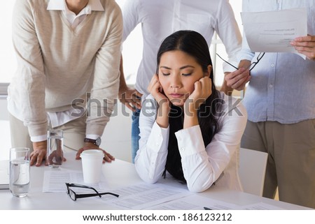 Stressed casual businesswoman surrounded by peers in the office Royalty-Free Stock Photo #186123212