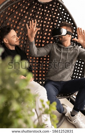 Amused gay couple testing the virtual reality glasses at home. High quality photo