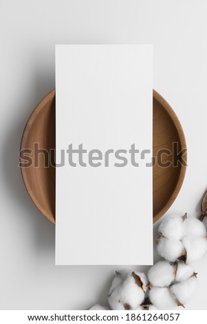 Menu card mockup on a wooden plate with a dried cotton branch, 4x9 ratio.