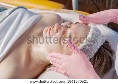 Professional beautician makes a facial massage to a woman.