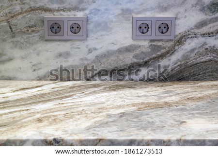 Beige marble table with electric outlets on stone wall texture background, suitable for advertise product display presentation backdrop and mock up