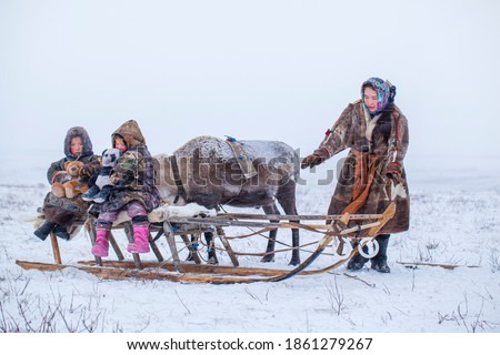The Yamal Peninsula, the extreme north. Happy boy and girl on reindeer herder pasture in a cold winter day, polar circle, children and animals. Royalty-Free Stock Photo #1861279267
