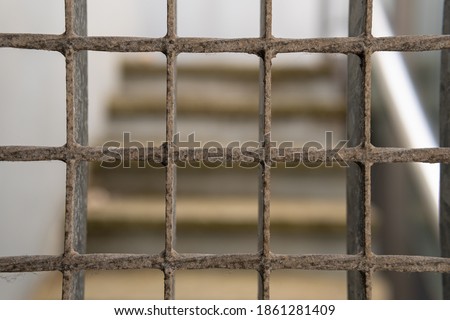 Deteriored iron fence. At the background of the image an unfocused staircase. Urban image