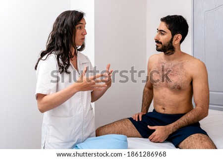 Stock photo of physiotherapist talking to patient sitting in stretcher.