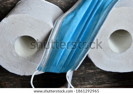 Blue face mask and roll of three toilet paper on an old wooden board background. Sign of Satan 666, Copy space, covid - 19