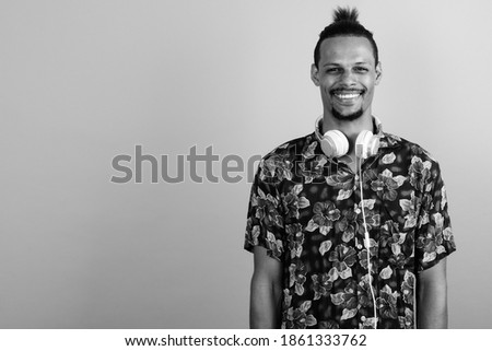 Happy young bearded handsome African man wearing headphones
