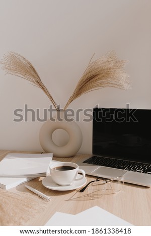 Female home office desk workspace. Blank screen laptop computer with copy space. Coffee cup, pampas grass in stylish vase on beige wooden table. Minimalist lifestyle blog mockup. Royalty-Free Stock Photo #1861338418