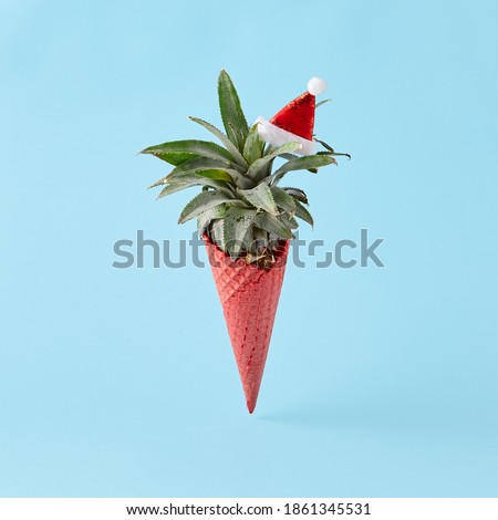 Red ice cream cone with pineapple and santa  on pastel blue background. Creative minimal christmas concept