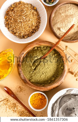 Ingredients for homemade skin and hair care in bowls top view. Henna powder, dry chamomile, turmeric, cosmetic clay, and oil. Ayurvedic skin care products.