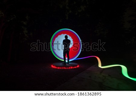 One person standing alone against beautiful red green white circle light painting as the backdrop