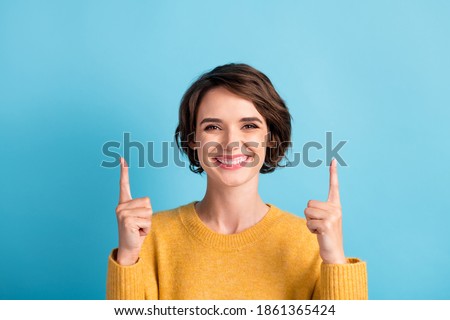 Photo portrait of happy smiling girl with bob hairstyle pointing up at empty space with fingers isolated on vibrant blue color background