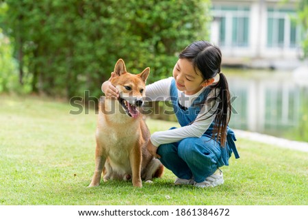 Pet lover An Asian girl is playing with a Shiba Inu dog in the park in the spring. Royalty-Free Stock Photo #1861384672