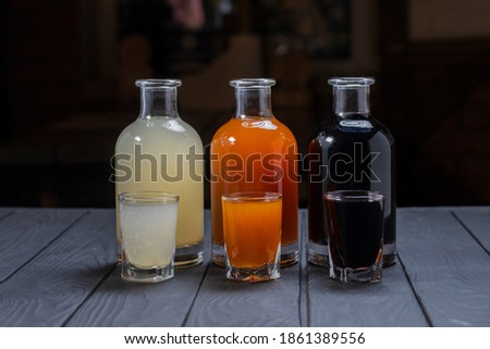 Assorted alcoholic cordials in glasses and decanters on dark wood background Royalty-Free Stock Photo #1861389556