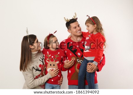 Family in Christmas sweaters and festive headbands on white background