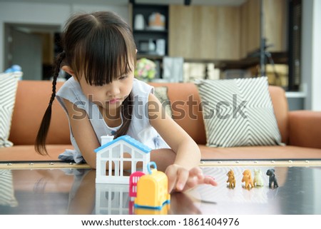 Asian little girl kids playing alone with plastic house toys in living room or well-lit modern home, Development of young children is creative by the imagination of children concept.