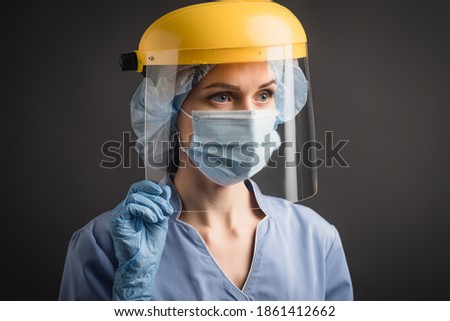 nurse in medical mask, cap and face shield isolated on dark grey